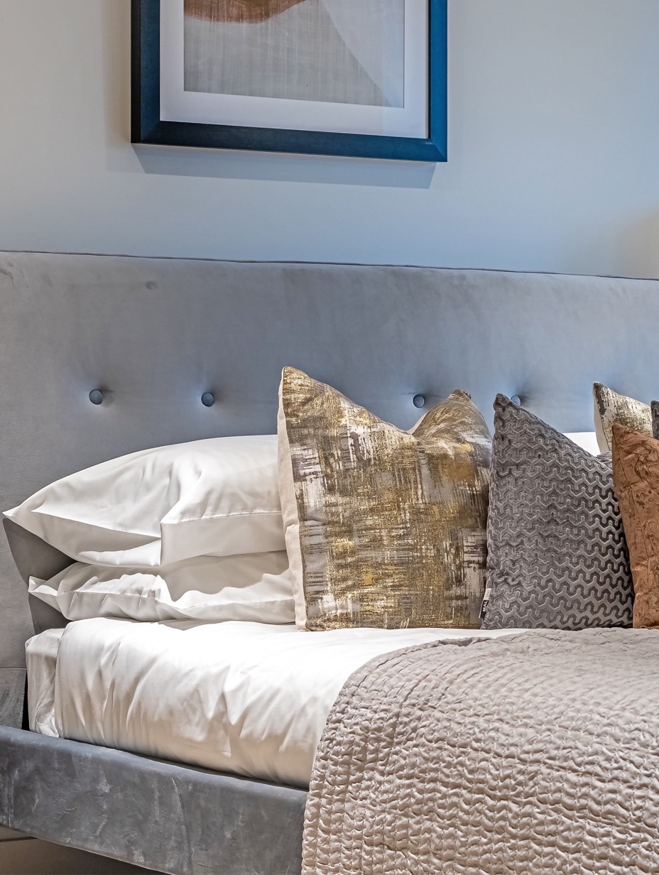 A bedroom in a Zen home, made up with a grey upholstered bed