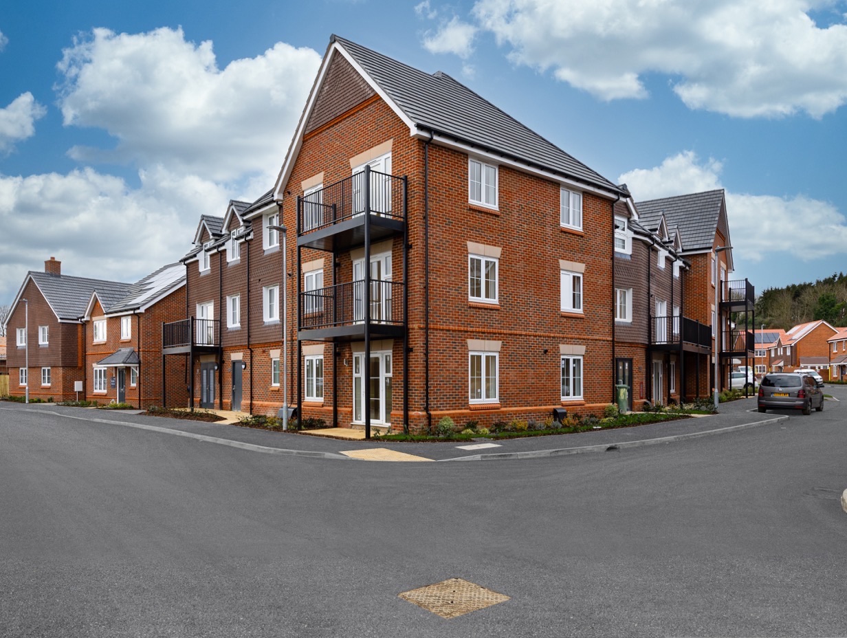 A newly built block of red brick flats with balconies on a Zen scheme