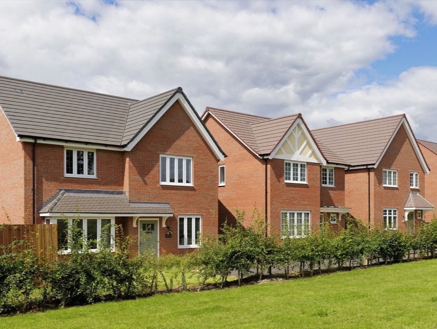 A row of new red brick family houses with tiled roofs and front gardens